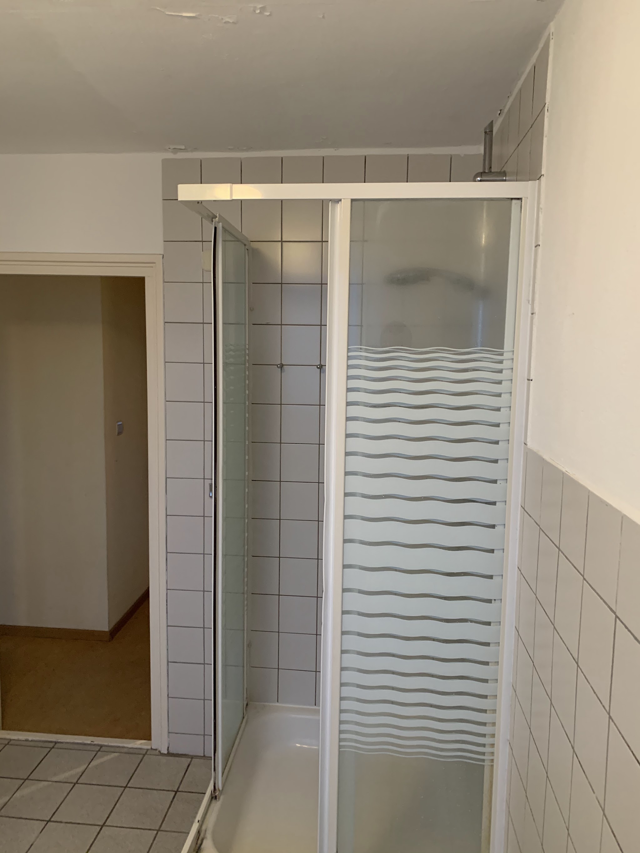 Bestaande badkamer met witte tegels en douchecabine